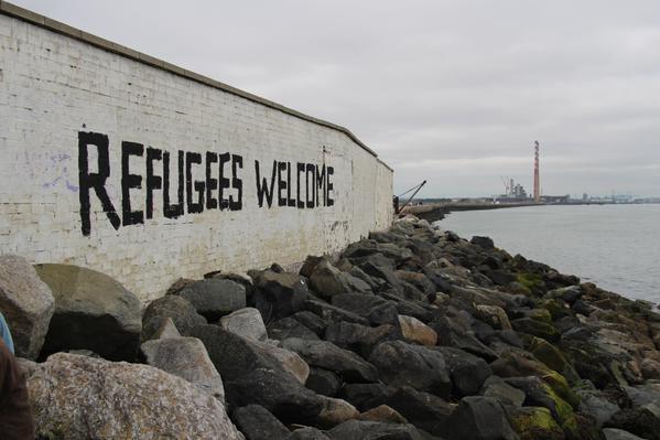 Coastal wall with 'refugees welcome' written on it